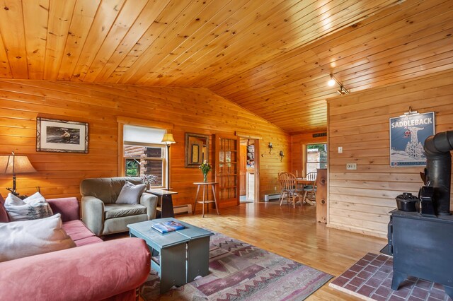 62 Antler Way, Rangeley, ME 04970 - living room featuring a wood stove, vaulted ceiling, wooden walls, a baseboard heating unit, and wood finished floors