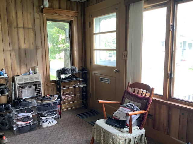 interior space with carpet floors, heating unit, and wood walls