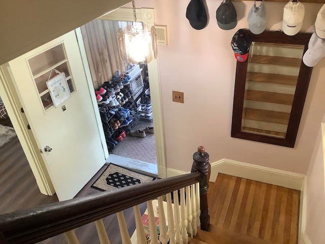 stairs featuring wood-type flooring and a chandelier