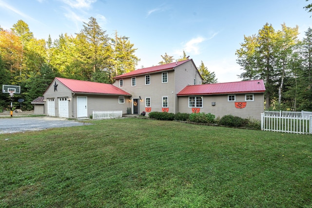 rear view of property featuring a garage, a yard, and an outbuilding