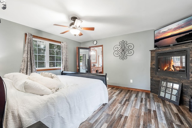 bedroom featuring a multi sided fireplace, dark hardwood / wood-style flooring, and ceiling fan