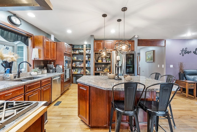 kitchen featuring pendant lighting, sink, appliances with stainless steel finishes, a center island, and light wood-type flooring