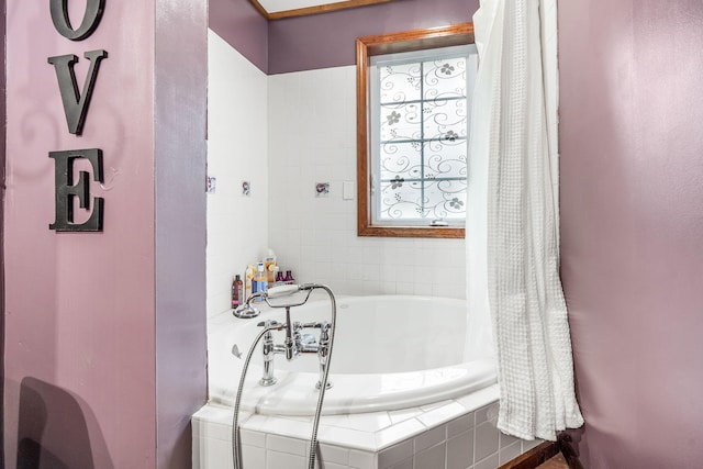 bathroom with tiled tub and a healthy amount of sunlight