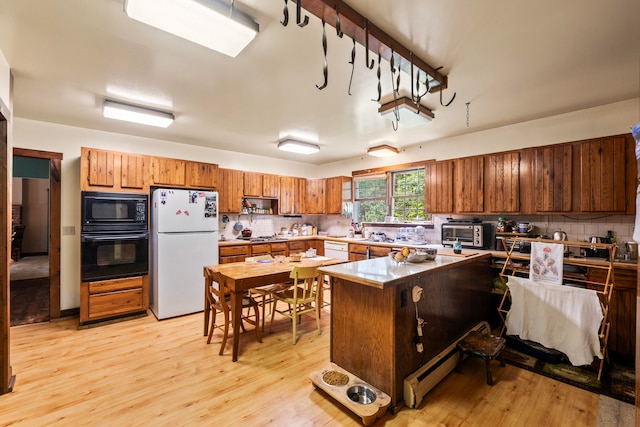 kitchen featuring black appliances, light hardwood / wood-style floors, and tasteful backsplash