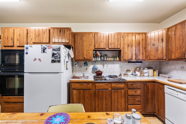 kitchen featuring light wood-type flooring, tasteful backsplash, and black appliances