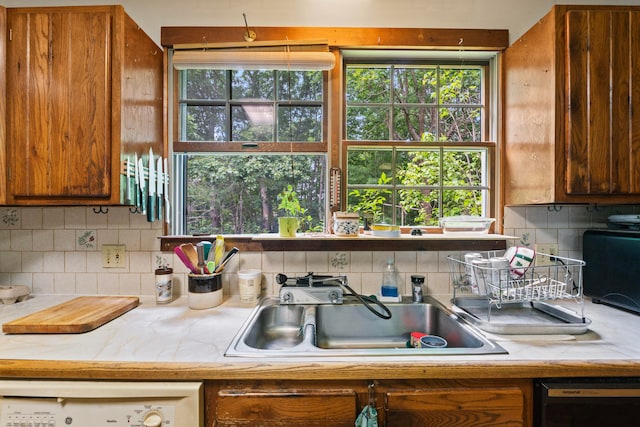 kitchen with black dishwasher, tasteful backsplash, and sink