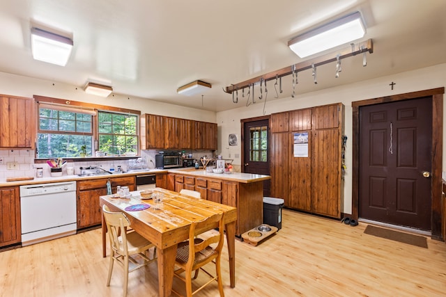 kitchen featuring backsplash, light hardwood / wood-style floors, a center island, and white dishwasher