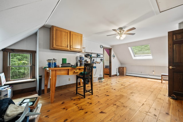 home office featuring a baseboard heating unit, vaulted ceiling with skylight, ceiling fan, and light wood-type flooring