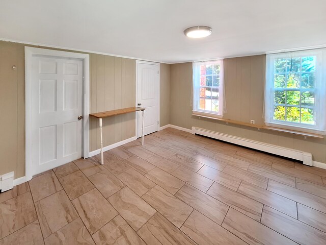 unfurnished bedroom with a baseboard radiator and wood walls