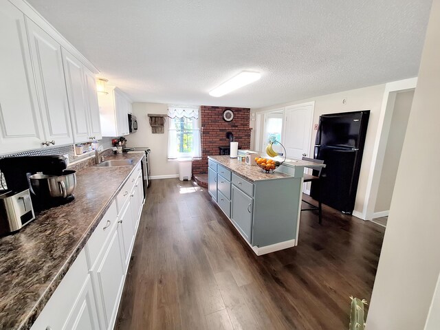 kitchen featuring a kitchen island, a textured ceiling, dark wood-type flooring, white cabinetry, and appliances with stainless steel finishes