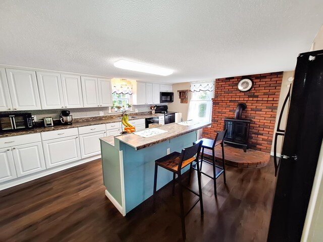 kitchen featuring black appliances, a textured ceiling, dark wood-type flooring, and white cabinetry