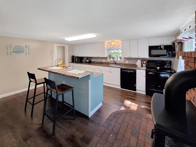 kitchen with sink, white cabinetry, a kitchen bar, black appliances, and a center island with sink