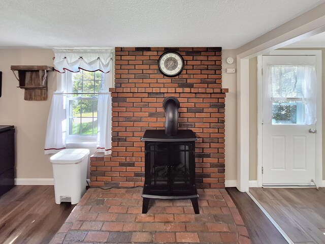 interior space with a wood stove, wood-type flooring, and a textured ceiling