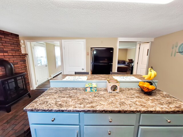 kitchen featuring dark hardwood / wood-style flooring, black refrigerator, a textured ceiling, a center island, and a baseboard radiator