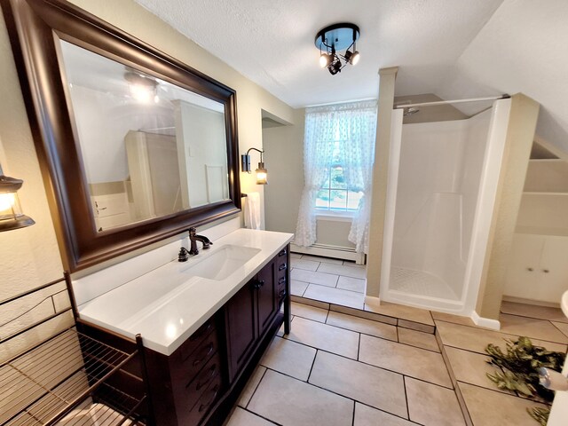 bathroom with curtained shower, vanity, a textured ceiling, tile patterned flooring, and a baseboard heating unit