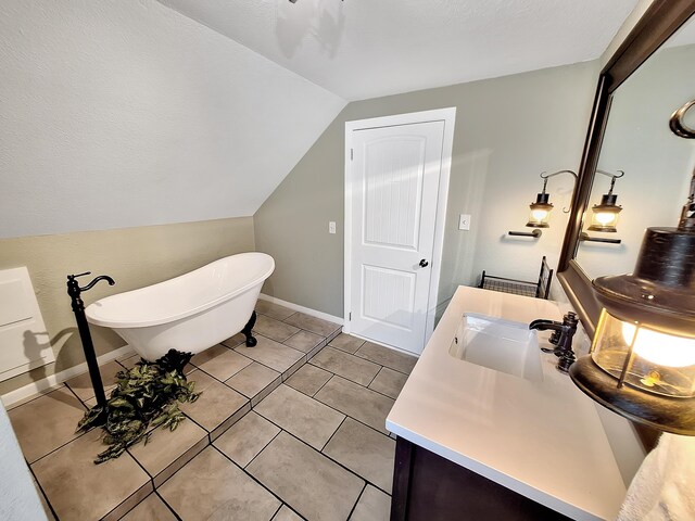 bathroom featuring tile patterned flooring, vaulted ceiling, vanity, and a bathtub