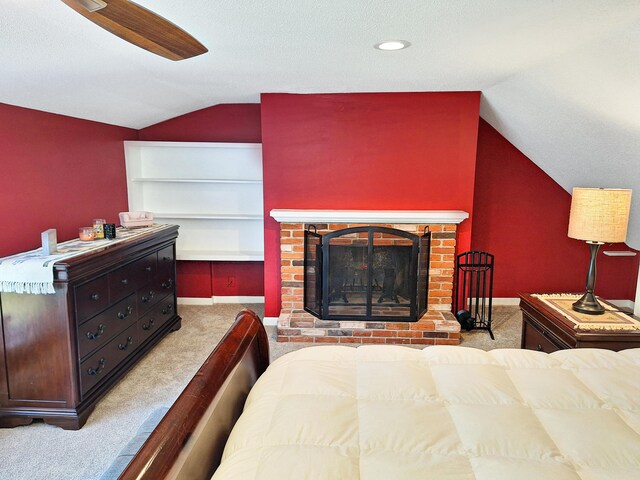 bedroom with a brick fireplace, lofted ceiling, a textured ceiling, and light colored carpet