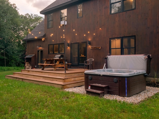 rear view of house featuring a deck, a yard, and a hot tub