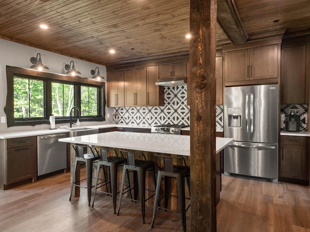 kitchen with a center island, dark hardwood / wood-style floors, sink, a kitchen breakfast bar, and appliances with stainless steel finishes