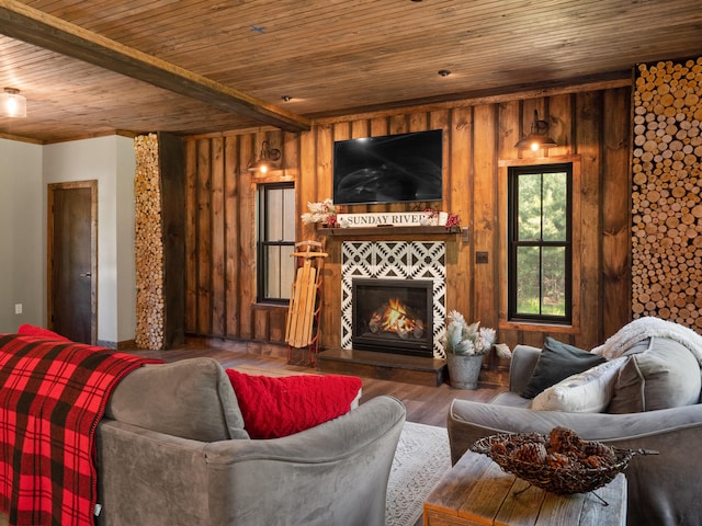 living room with beamed ceiling, a tile fireplace, wood-type flooring, wooden walls, and wooden ceiling