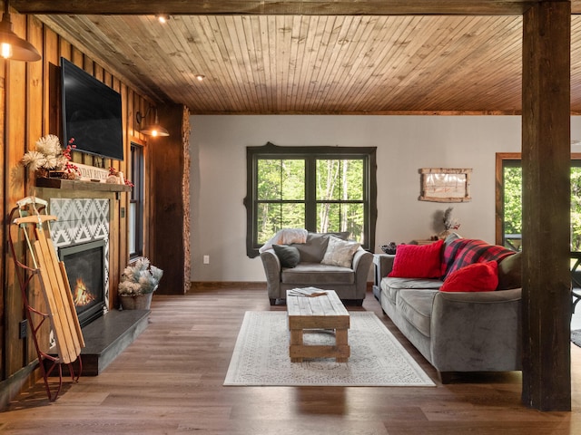 living room with a tiled fireplace, wood walls, wooden ceiling, and hardwood / wood-style floors