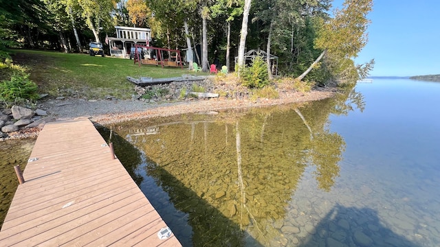 view of dock with a water view and a lawn