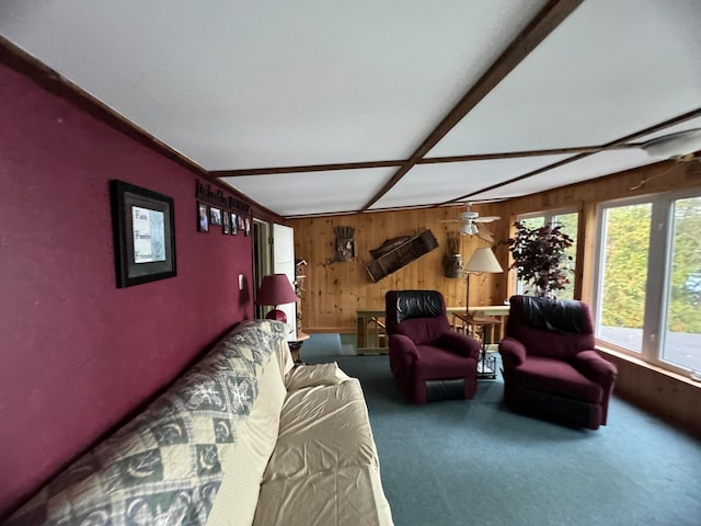 living room with ceiling fan, wood walls, and carpet