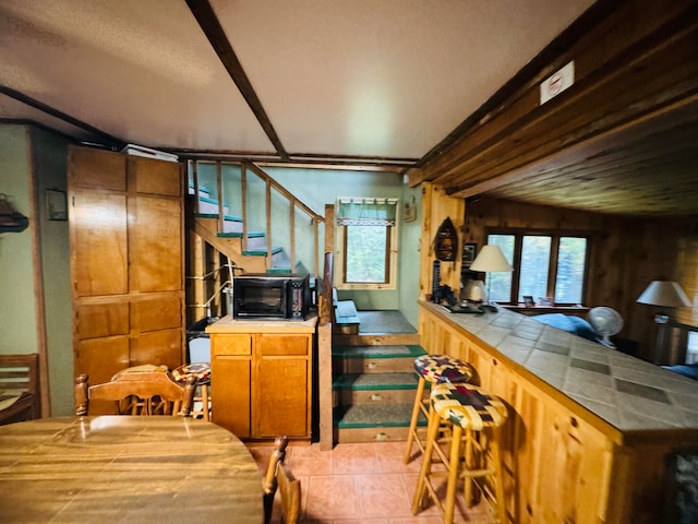 kitchen with light tile patterned floors, wooden walls, and tile countertops