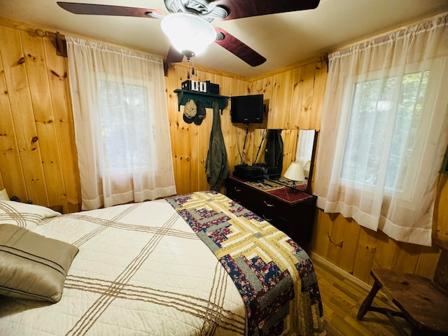 bedroom featuring wooden walls, ceiling fan, and wood-type flooring