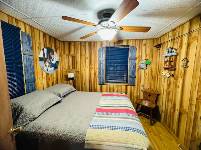 bedroom featuring wooden walls, ceiling fan, and wood-type flooring