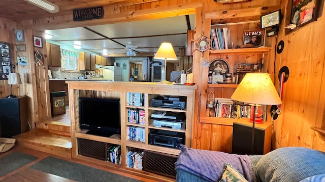 interior space with ceiling fan, wood walls, and white fridge