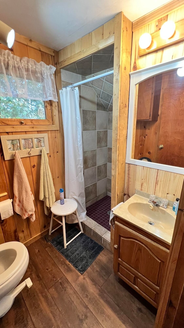 bathroom featuring wood-type flooring, vanity, wooden walls, and a shower with curtain