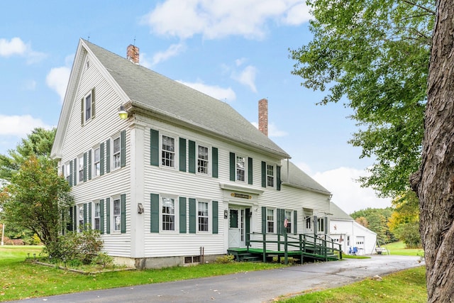 colonial home featuring a front yard and a wooden deck