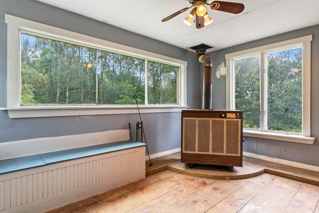 interior space with ceiling fan, plenty of natural light, and a wood stove