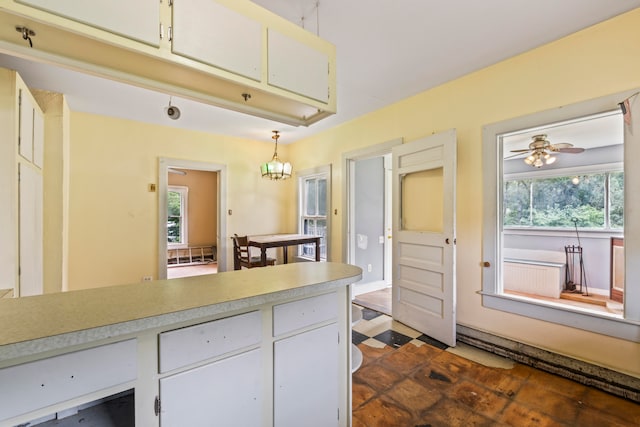 kitchen with ceiling fan with notable chandelier, white cabinetry, a healthy amount of sunlight, and decorative light fixtures