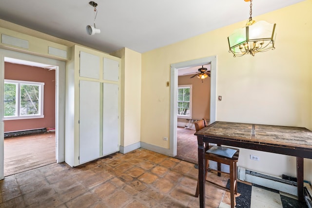 interior space featuring pendant lighting, ceiling fan with notable chandelier, plenty of natural light, and a baseboard heating unit