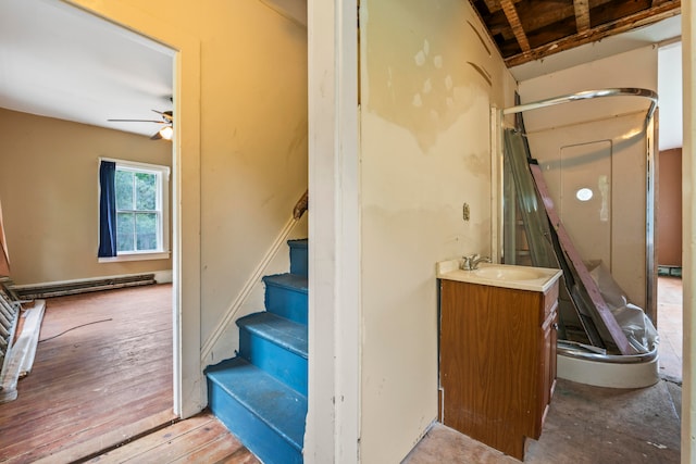 stairway featuring a baseboard radiator, wood-type flooring, ceiling fan, and sink