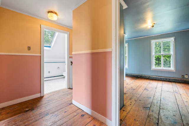 hall featuring crown molding, a wealth of natural light, a baseboard heating unit, and hardwood / wood-style flooring