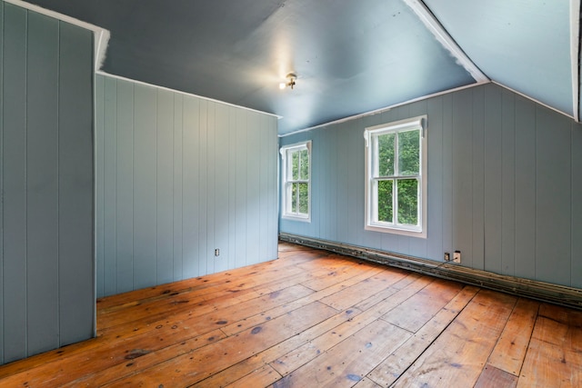 additional living space featuring wood walls, light hardwood / wood-style floors, and vaulted ceiling