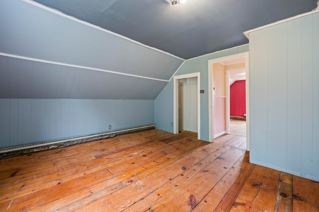 bonus room featuring light wood-type flooring, wooden walls, and vaulted ceiling