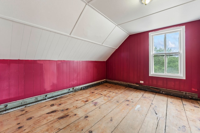 bonus room with wood walls, vaulted ceiling, and light hardwood / wood-style flooring