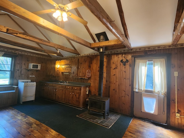 kitchen with vaulted ceiling with beams, white appliances, dark hardwood / wood-style floors, and a wood stove