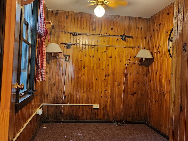 carpeted empty room featuring wooden walls and ceiling fan