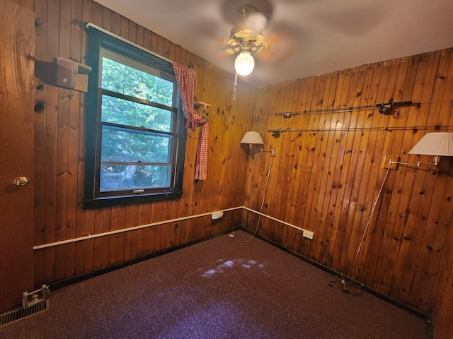 spare room with ceiling fan, wooden walls, and carpet