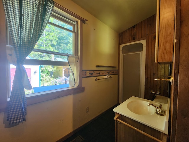 bathroom featuring vanity, wooden walls, and vaulted ceiling