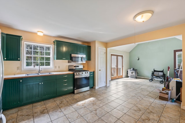 kitchen featuring stainless steel appliances, green cabinetry, light tile patterned floors, and sink