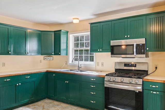 kitchen with green cabinetry, sink, and stainless steel appliances