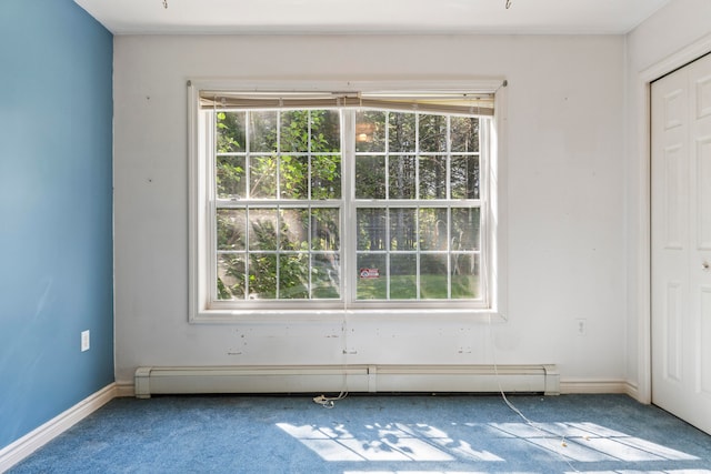 carpeted empty room featuring a baseboard heating unit