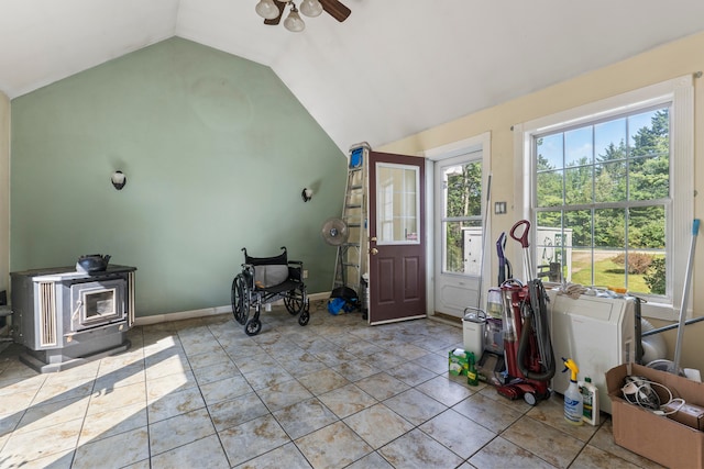 tiled entryway featuring a wood stove, vaulted ceiling, and ceiling fan