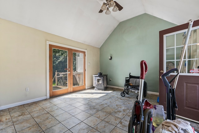 exercise area with a wood stove, vaulted ceiling, ceiling fan, and light tile patterned floors